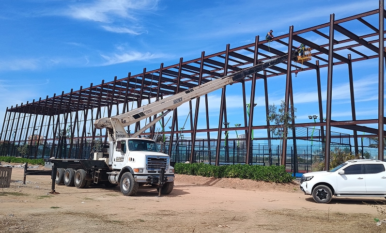 Grúa instalando estructura metálica en proyecto industrial al aire libre.