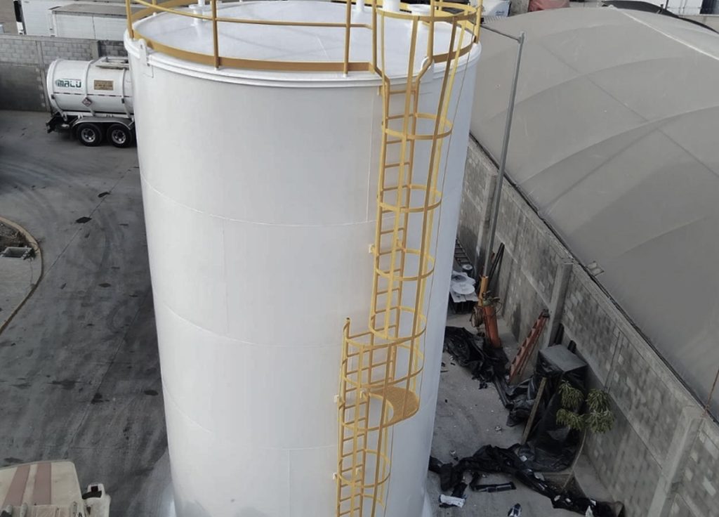 Tanque de almacenamiento con escaleras de seguridad en planta industrial.